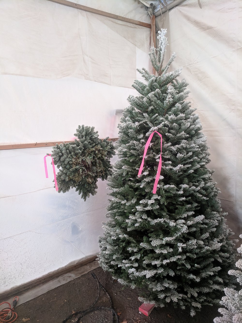 A flocked fir with a pink tag in the tent, next to a matching flocked wreath
